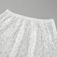 Close-up of a high-waisted white lace maxi skirt, showcasing the intricate floral lace pattern and the integrated waistband. The fabric is sheer and matte, with a delicate texture.