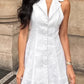 A white linen-blend halter neck A-line mini dress is modeled outdoors, featuring a wide collar, button-front detail, and a flared skirt.
