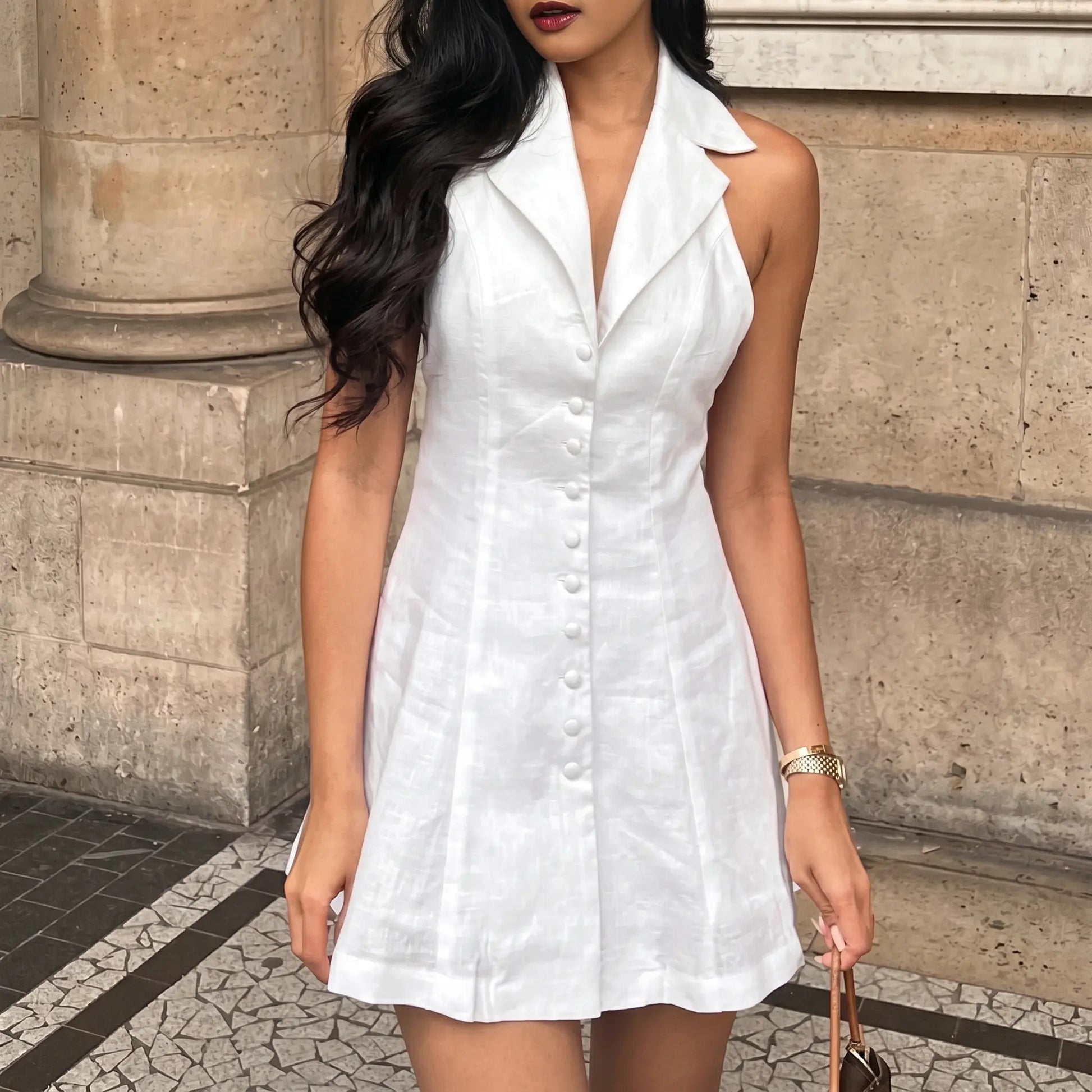 A white linen-blend halter neck A-line mini dress is modeled outdoors, featuring a wide collar, button-front detail, and a flared skirt.