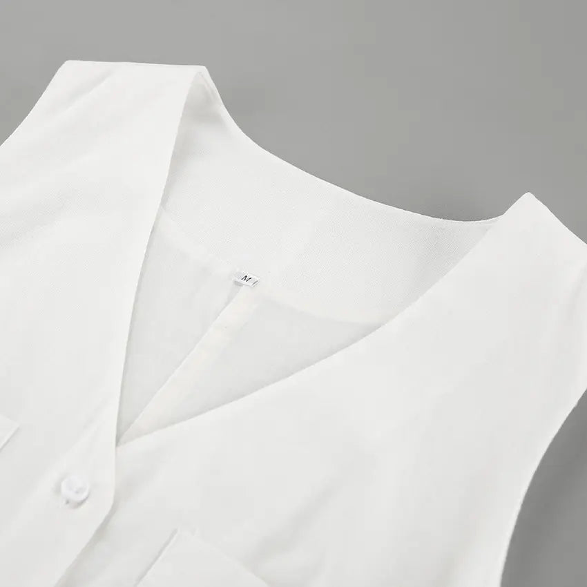 Close-up of a white linen-blend V-neck romper, showcasing the fabric texture, button detail, and chest pocket. The sleeveless design is visible.
