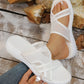 Model's foot wearing a white mesh wedge sandal with criss-cross straps, showcasing the comfortable open-toe design and stable wedge sole on a rustic wooden background.