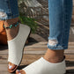 Women's white perforated PU leather flat peep-toe sandals worn with distressed denim jeans, showcasing a casual summer style on a wooden deck.