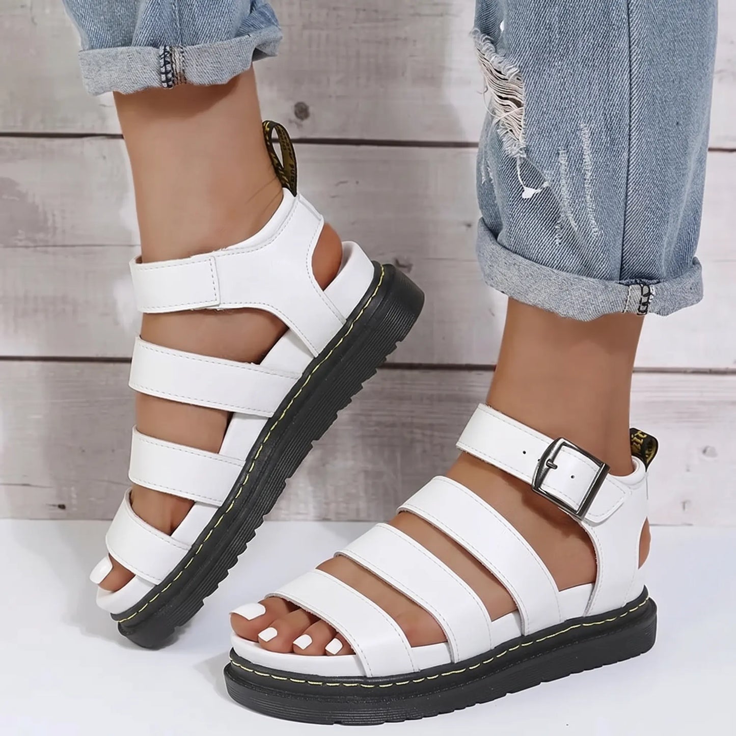 White Zylphos platform gladiator sandals with three PU leather straps and a side ankle buckle, featuring a 3cm black treaded sole with yellow stitching.