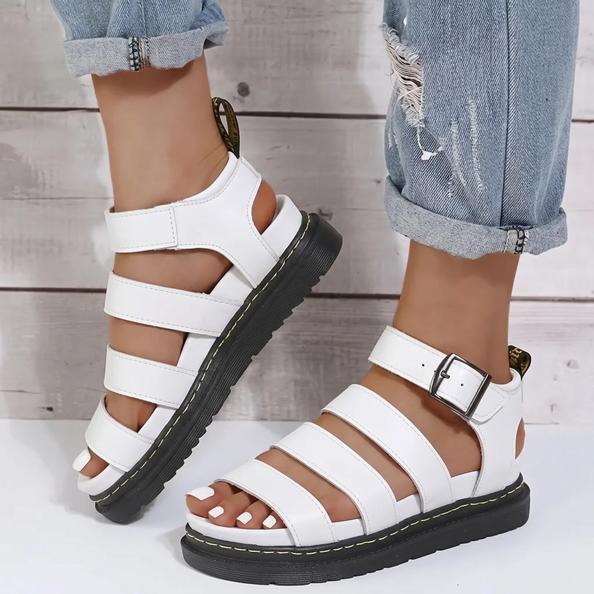 White Zylphos platform gladiator sandals with three PU leather straps and a side ankle buckle, featuring a 3cm black treaded sole with yellow stitching.