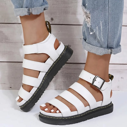 White Zylphos platform gladiator sandals with three PU leather straps and a side ankle buckle, featuring a 3cm black treaded sole with yellow stitching.