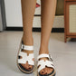 White platform slide sandals with H-strap silhouette and adjustable buckle worn on feet, showcasing the layered sole and comfortable fit.