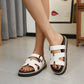 Chic white platform slides styled on a woman's feet, featuring an 'H' strap design, adjustable gunmetal buckle, and a 5cm layered sole with white contrast stitching.