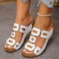 White Kyorin platform wedge sandals adorned with gold geometric embellishments, shown on a model's foot with a pearl anklet against a grey tiled background.