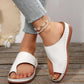 White PU leather casual slide sandals with a toe-post design, contoured footbed, and stitched sole detail, worn on feet with jeans and an anklet against a wooden background.