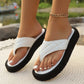 Close-up of white quilted PU platform thong sandals worn by a person with a gold anklet, showcasing the textured straps and thick sole in a natural setting.