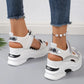 White sporty platform sandals adorned with shimmering rhinestones, featuring adjustable hook-and-loop straps and a chunky sole, shown on feet with denim.