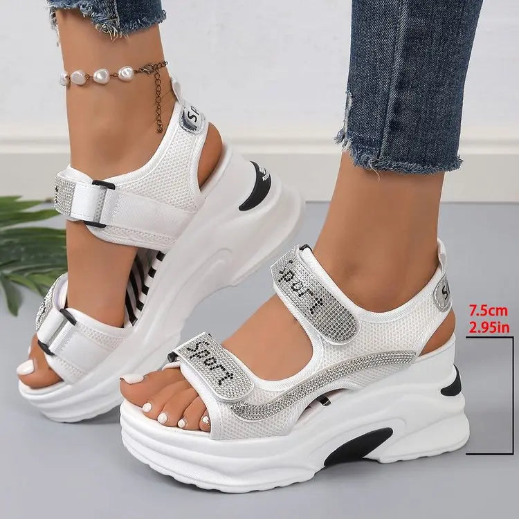 White sporty chic platform sandals adorned with sparkling rhinestones and "SPORT" text, featuring adjustable hook-and-loop straps and a thick sculpted sole, shown on feet with a measurement indicator.