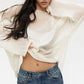 Zomari pristine white sheer bell sleeve knit sweater on a model, showcasing its relaxed fit, delicate open-knit texture, and flowing bell sleeves.