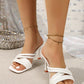 White strappy heeled sandals with a square toe mule silhouette, featuring multiple thin, glossy PU straps. Worn on feet with delicate gold anklets against a sparkly textured background.