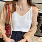 Crisp white Koryx waffle knit camisole featuring thin spaghetti straps and a V-neck, worn by a model in a relaxed lifestyle setting. The top highlights its distinctive texture.