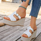 Women's white woven platform espadrille wedge sandals with T-strap and buckle closure, styled with denim jeans and a turquoise anklet.