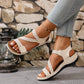 Women's cream comfort sport sandals with criss-cross elastic straps and beige faux leather accents shown on a model's feet wearing light-wash jeans.