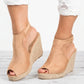 Women's light tan espadrille wedge sandals with peep-toe front and adjustable ankle strap, worn with distressed white jeans.