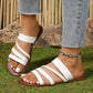 Women's white braided strap summer slide sandals, worn on feet with blue jeans, showcasing the flat sole and bohemian style.