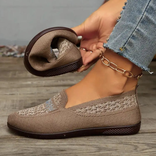 Women's warm beige breathable knit loafers featuring a geometric pattern and delicate crystal embellishment on the vamp, styled with denim jeans on a wooden floor.