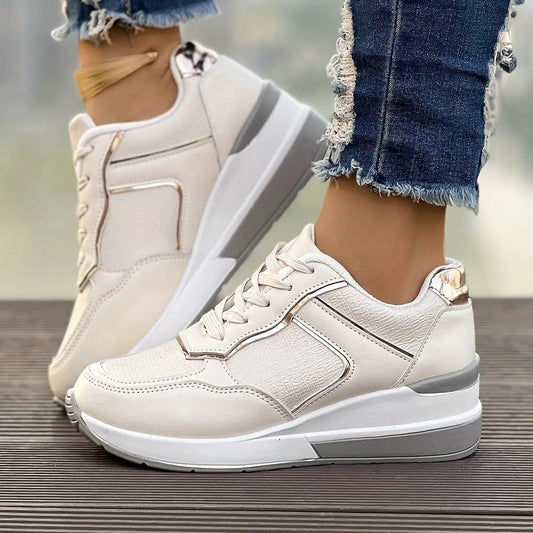 Women's off-white wedge sneakers with textured knit panels and subtle rose gold metallic accents, shown in a three-quarter view and worn with ripped denim jeans.