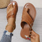 Women's tan brown leather toe-thong sandals with crisscross straps and a silver buckle, shown on a foot with distressed jeans and anklet. Features white contrast sole stitching.