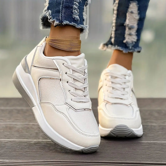Women's off-white low-top sneakers with textured panels and subtle rose gold metallic accents, worn with ripped denim jeans and a gold anklet on a wooden surface.