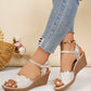 Women's Xanthi pale gold peep-toe wedge sandals with delicate sequined floral embroidery, polished gold trim, and an adjustable ankle strap, styled with distressed denim jeans.