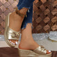 Xyloen women's gold metallic wedge slide sandals with a chunky chain detail across the peep-toe strap. Features a textured wedge heel and platform sole, shown on a model's foot with blue jeans.
