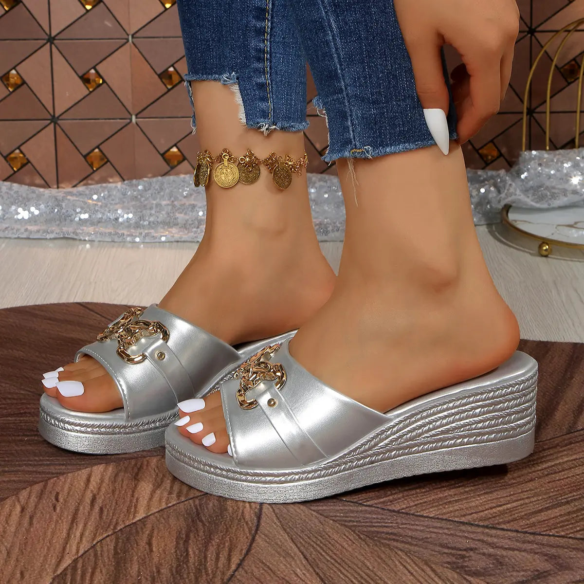 Silver Xyloen women's wedge slide sandals with a chunky metallic chain detail, peep-toe design, and textured wedge heel, styled with blue jeans.
