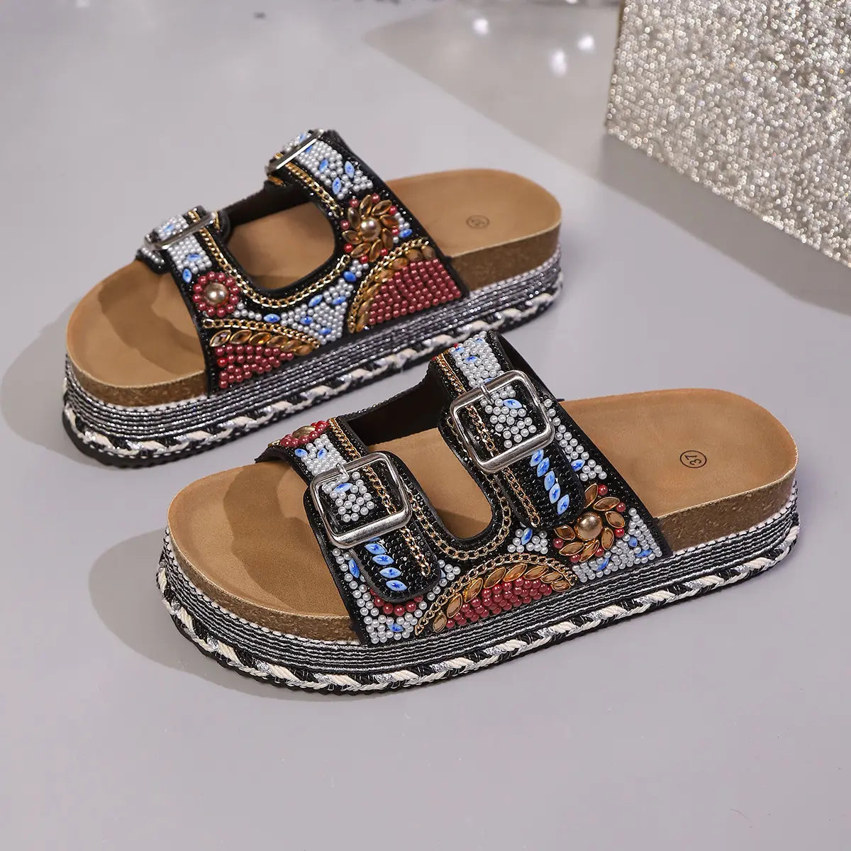 Platform slide sandals in rose pink fabric embellished with intricate beads and sequins, featuring double adjustable buckle straps and a cork-effect platform sole.