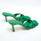Emerald green Xylos square-toe stiletto mules with a knotted strap detail and a 7cm flared heel, shown from a three-quarter angle on a white background.