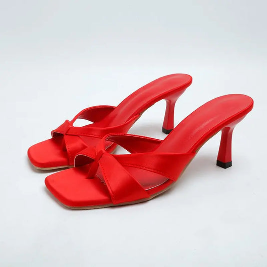 Elegant red Xylos square-toe stiletto sandals featuring a thong toe post and crossed straps with a knot detail, presented on a clean white studio background.