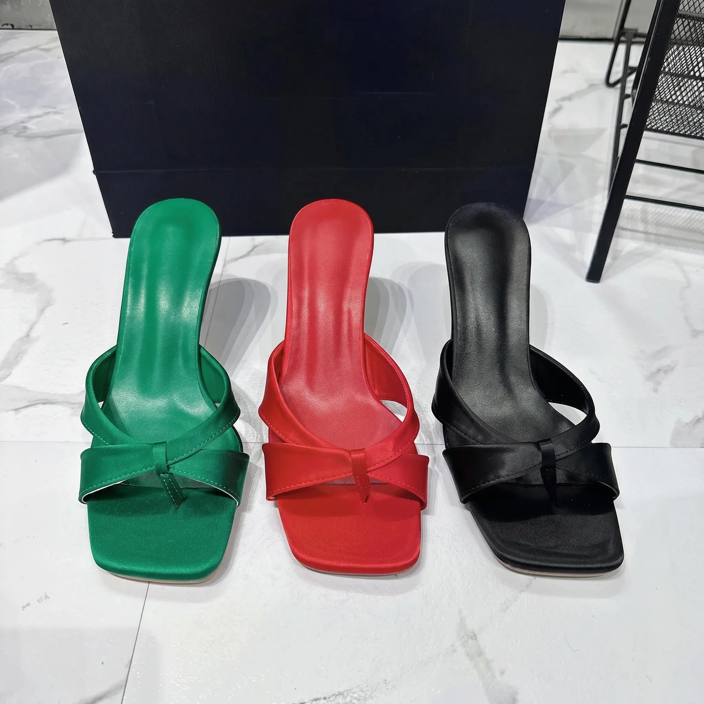 Three pairs of Xylos Square Toe Stiletto Sandals in Black, Scarlet Red, and Emerald Green, presented from the front on a clean studio floor.