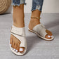 A pair of Xylyn women's ivory leather flat sandals with a toe-thong design and crisscross straps, worn with distressed denim jeans and a gold anklet.