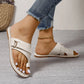 Women's Xylyn ivory leather flat sandals with a toe-thong design and crisscross straps featuring an adjustable silver-tone buckle. Shown styled with denim jeans and an anklet.