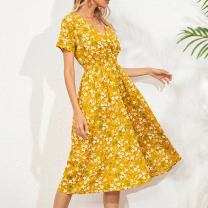 A yellow midi dress with a ditsy floral print, featuring short flutter sleeves, a V-neckline, and a cinched smocked waist, worn by a model against a white textured background.