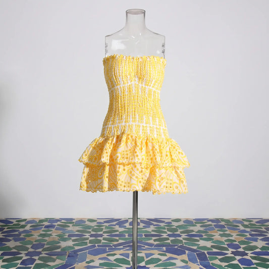 Yellow strapless mini dress with smocked bodice, tiered eyelet-embroidered ruffle skirt, and scalloped edges, front view on mannequin.