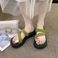 Olive green Zalva platform thong sandals worn on feet, featuring plush straps and a gold circular buckle, styled with a white handbag and magazine.