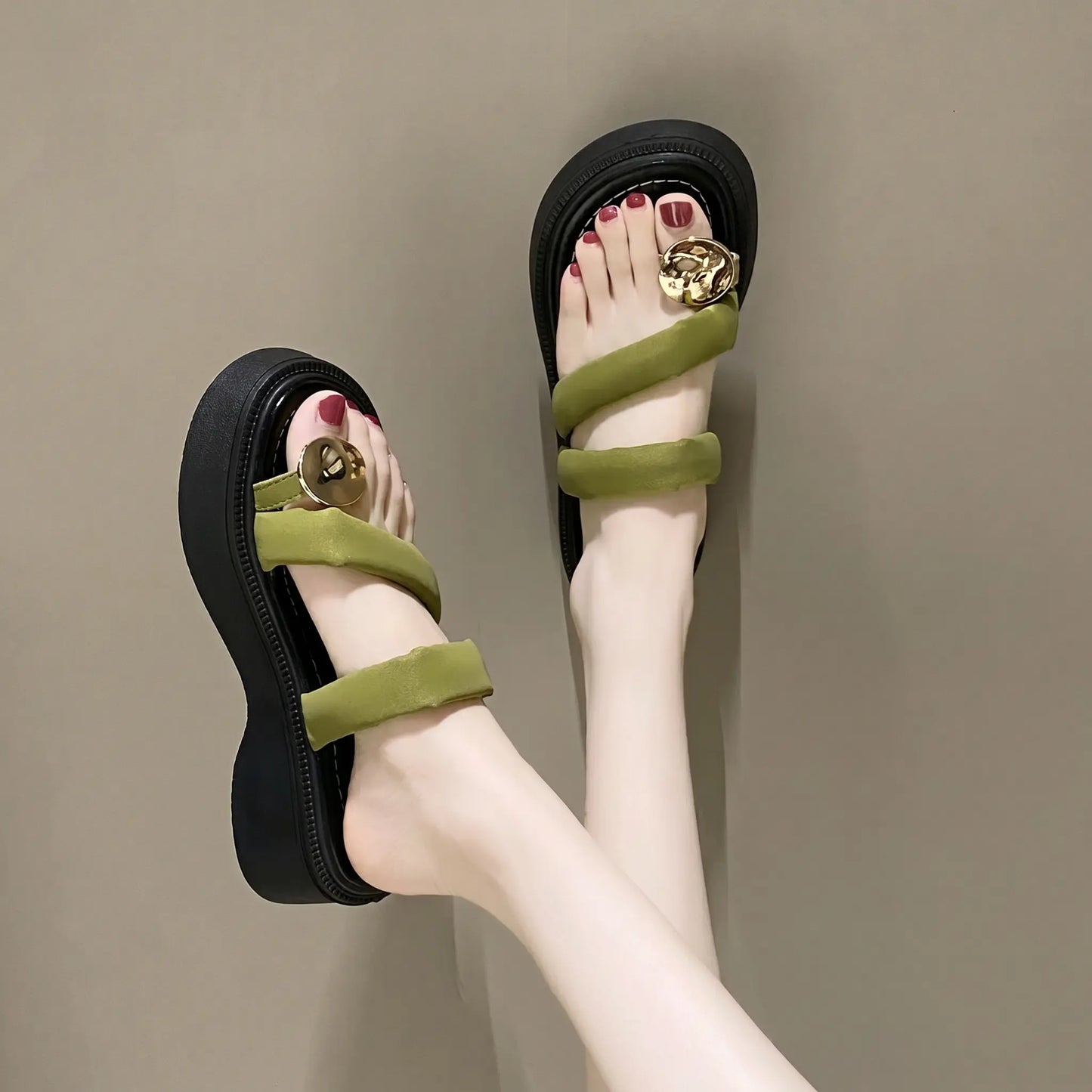Olive green platform thong sandals worn on feet, featuring plush velvet-feel straps, gold-tone circular buckle, and a chunky layered sole.