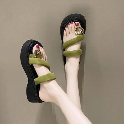Olive green platform thong sandals worn on feet, featuring plush velvet-feel straps, gold-tone circular buckle, and a chunky layered sole.