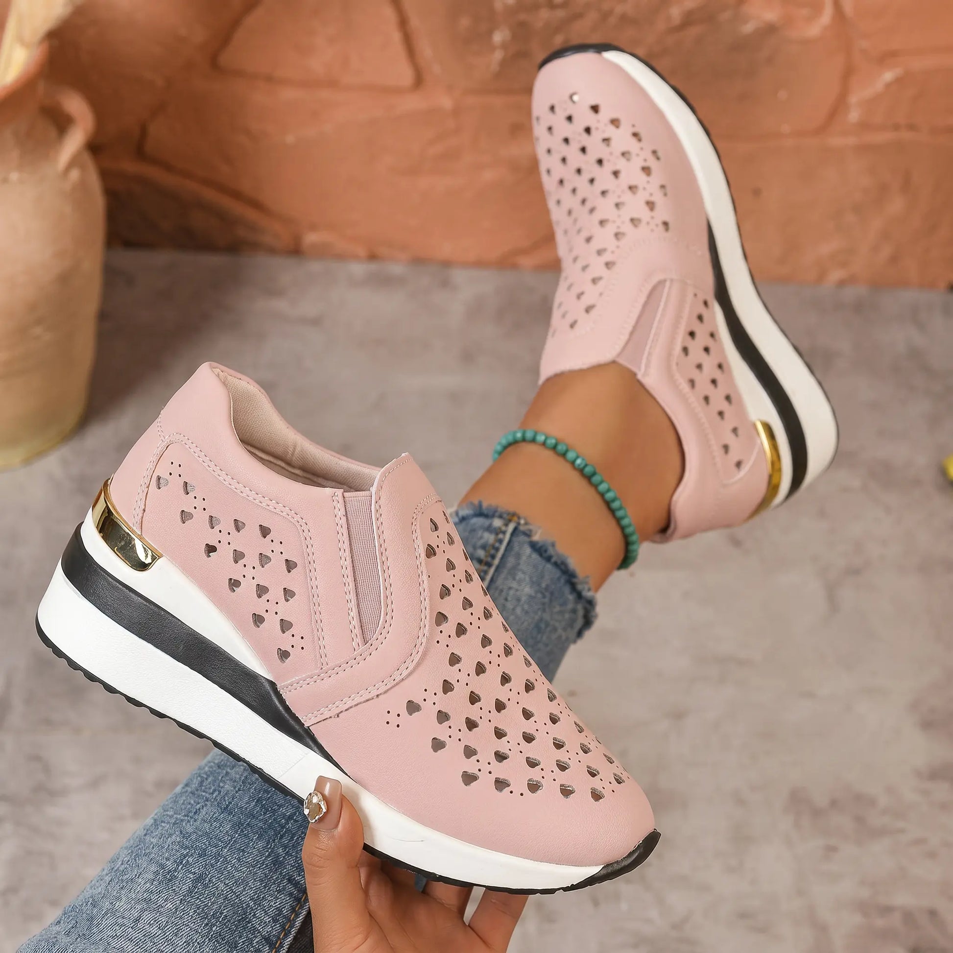 Zayna women's dusty rose perforated heart wedge loafers shown on foot, offering a blend of bohemian charm and elegant comfort with a gold heel accent.