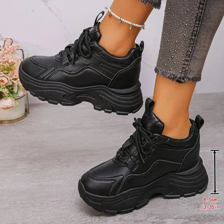 Black Zelpha chunky platform sneakers shown on feet, styled with embellished grey denim jeans and a pearl anklet, highlighting the 8.5cm sole height.