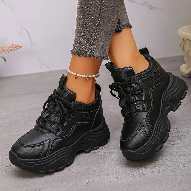 Black Zelpha chunky platform sneakers crafted from synthetic leather, showcasing a lace-up front and lugged sole, worn with embellished jeans and an anklet.