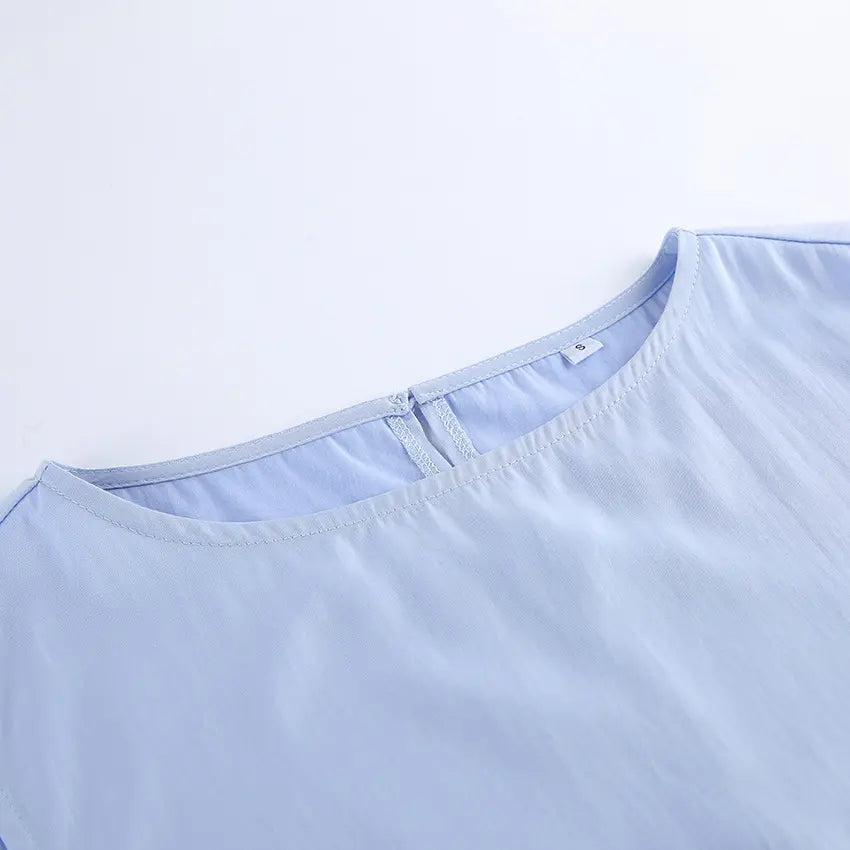 Close-up of the soft lilac-blue Zelphira bohemian set top, showing the crew neckline with a subtle zipper and a visible size 'S' tag, on a clean white background.