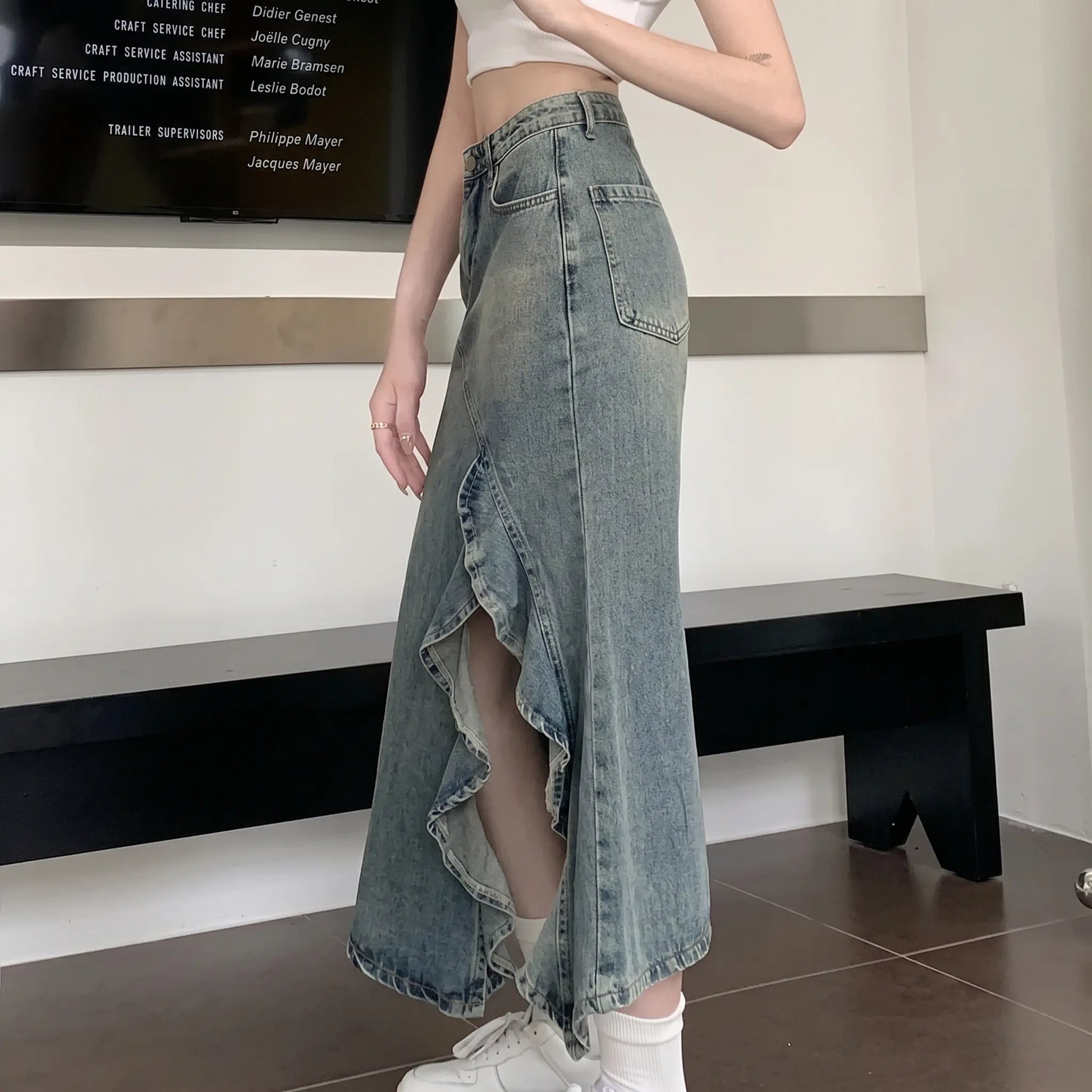 Zendru high-waisted vintage blue denim midi skirt on a woman, showcasing its asymmetrical ruffled front slit and elegant flowing silhouette.