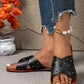 Zenoria black studded criss-cross strap slide sandals shown on feet with distressed denim jeans and a pearl anklet. Flat bohemian chic footwear for summer.