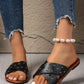 Zenoria black studded criss-cross strap flat slide sandals worn by a woman with distressed denim jeans and a pearl anklet.