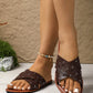 Close-up of women's brown Zenoria studded slide sandals with criss-cross perforated straps and a tan footbed, worn on feet with white toenails and a shell anklet.