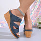 Dark blue perforated Zephira women's wedge sandals with peep-toe fish mouth, adjustable hook-and-loop strap, white contrast stitching, and wood-effect wedge heel, styled on a model with a sparkling anklet.